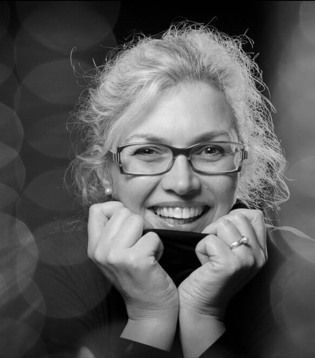 Marion Rottinghaus lacht, die Hände am Kragen ihres Rollkragenpullovers